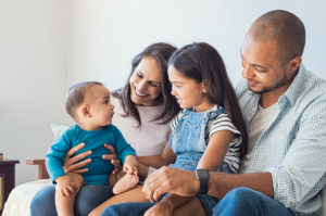 Happy family with baby and child sitting together on the couch