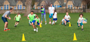 Children running in the field with yellow pylons