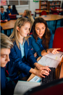 3 Educators sitting at a table with their text book open on the computer