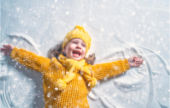 a child laying down on the snow making snow angels