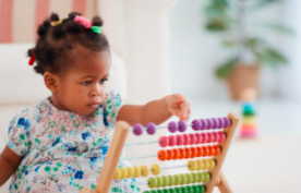 a toldder sitting on the floor with her bead counter