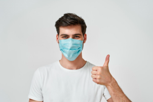 adult wearing a mask with his thumbs up